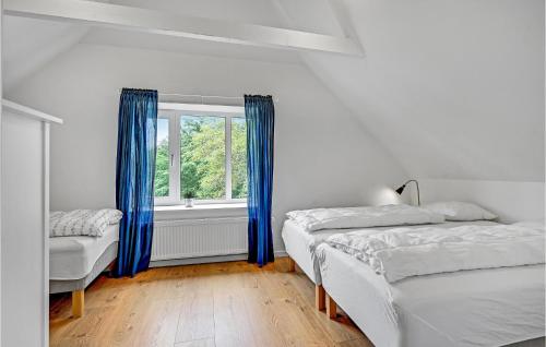 a bedroom with two beds and a window with blue curtains at Four-Bedroom Holiday Home In Grenaa in Brøndstrup