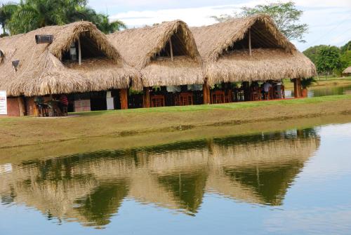 a house with thatched roofs reflecting in the water at Hotel Brisas La Gaviota Mariquit-Tolima in Mariquita