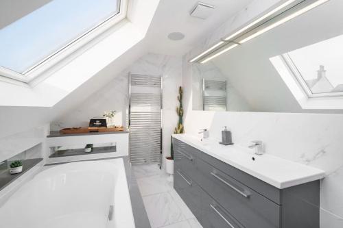 a white bathroom with two sinks and a tub at Beautiful 4 Bed Immaculate Condition Refurbished Property in Romford