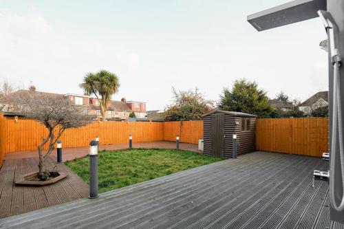 a backyard with a wooden deck and a fence at Beautiful 4 Bed Immaculate Condition Refurbished Property in Romford