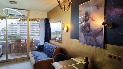 un salon avec un canapé et une grande peinture murale dans l'établissement L'ASTRONAUTE - Balcon vue mer - CLIM - place parking privée - Marina baie des anges, à Villeneuve-Loubet