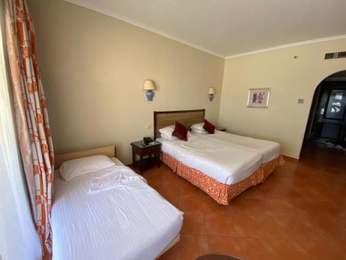 two beds in a hotel room with two bedsskirts at فندق بورتو مارينا - غرفة فندقية بخدمة فندقية in El Alamein