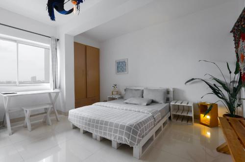 a white bedroom with a bed and a desk at Sixteen By Sixteen in Lagos