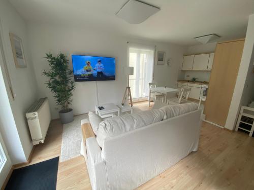 a living room with a white couch and a flat screen tv at Stilvolles Apartment mit Balkon, Küche & Parkplatz - Waldstetten Zentrum in Waldstetten