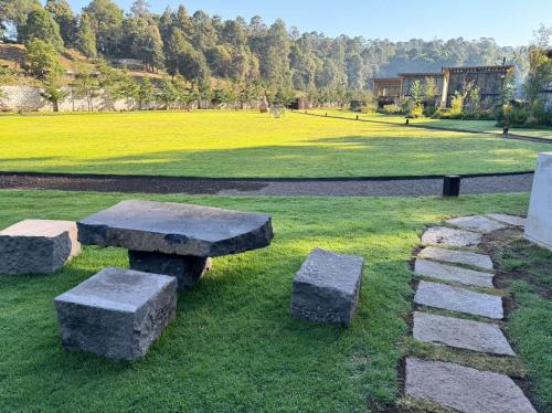 a park with two stone benches in the grass at Cabañas Avandaro Santo Boutique in Valle de Bravo