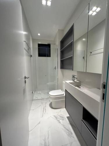 a white bathroom with a toilet and a shower at Flat 1609 Infinity Tower in Itapema