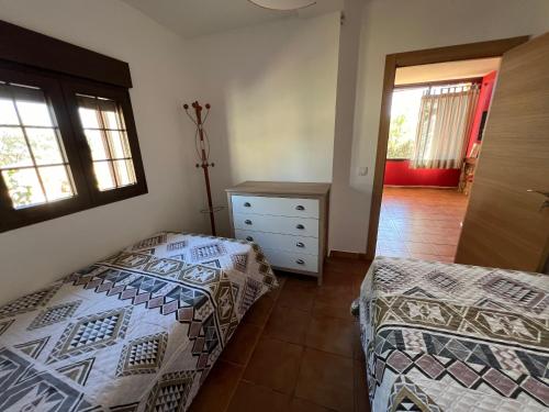 a bedroom with two beds and a dresser and windows at Villa Tranquila Lagunas de Ruidera in Ossa de Montiel