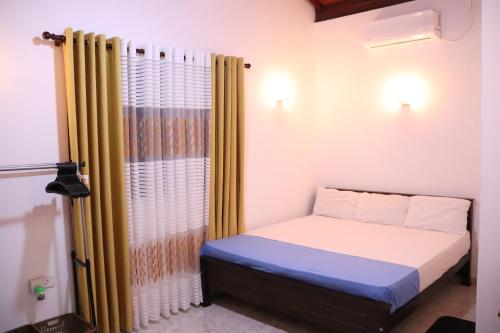 a small bedroom with a bed and a curtain at Dream Villa - Weligama in Weligama