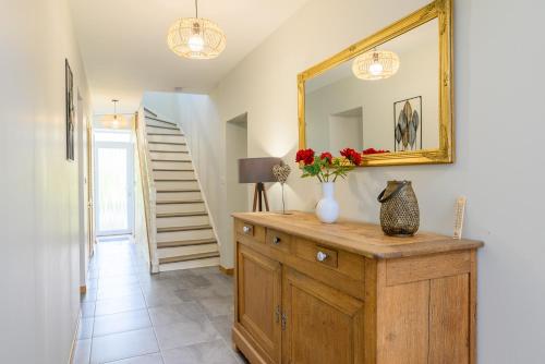 a room with a dresser with a mirror and flowers on it at Gîte des dix potiers in Raucourt-et-Flaba