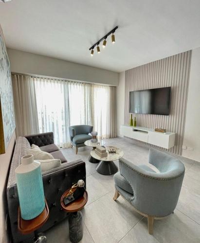 a living room with a couch and chairs and a tv at Bella Vista cozy-deluxe near Downtown center in Santo Domingo