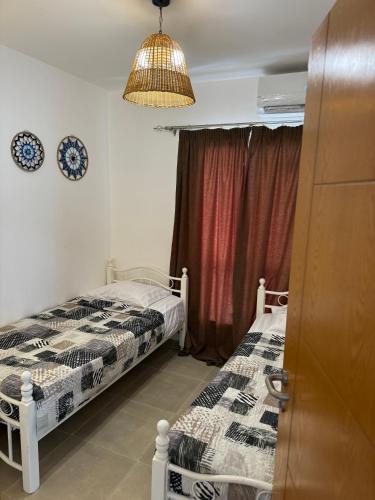 a bedroom with two beds and a chandelier at 3BR Chalet in MV Ras El Hekma in Ras Elhekma