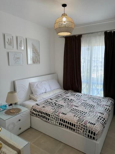 a bedroom with a bed and a chandelier at 3BR Chalet in MV Ras El Hekma in Ras Elhekma