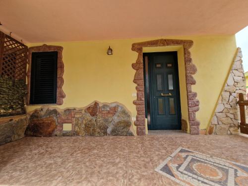 a house with a black door and a stone wall at Appartamento Dune in Santa Lucia