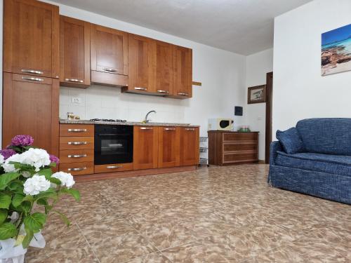 a kitchen with wooden cabinets and a blue couch at Appartamento Dune in Santa Lucia