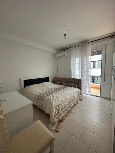 a white bedroom with a bed and a window at Apartament Rent Genti in Barç