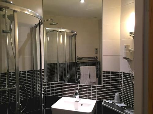 een badkamer met een wastafel, een douche en een spiegel bij Hôtel du Musée de l'Eau in Pont-en-Royans