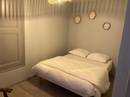 une chambre avec un lit avec des draps blancs et des oreillers dans l'établissement Appartement Hôtel de la Gare, à Château-du-Loir