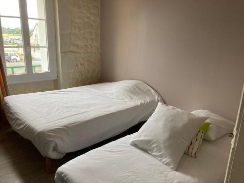 une chambre avec deux lits avec des draps blancs et une fenêtre dans l'établissement Appartement Hôtel de la Gare, à Château-du-Loir