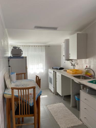 een keuken met witte kasten en een tafel en stoelen bij Casa Praia do Sul in Ericeira