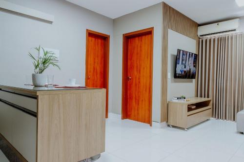 a room with two wooden doors and a tv in it at Bee Guest - Apartamentos de Temporada Luxxor Flat in Cuiabá