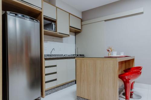 a kitchen with a stainless steel refrigerator and a red stool at Bee Guest - Apartamentos de Temporada Luxxor Flat in Cuiabá