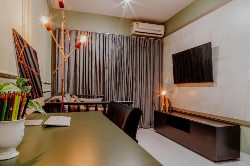 a living room with a table and a television at Bee Guest - Apartamentos de Temporada Luxxor Flat in Cuiabá