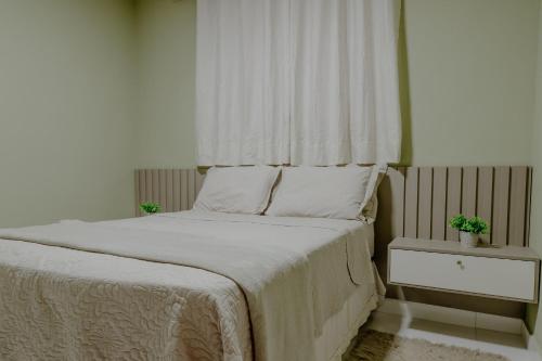 a bedroom with a bed with white sheets and a window at Bee Guest - Apartamentos de Temporada Luxxor Flat in Cuiabá