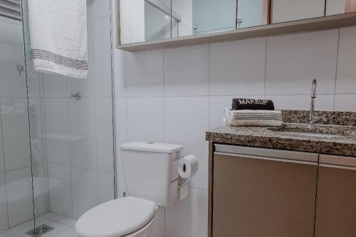a white bathroom with a toilet and a sink at Bee Guest - Apartamentos de Temporada Luxxor Flat in Cuiabá