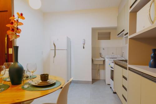 a kitchen with a table and a white refrigerator at Bee Guest - Apartamentos de Temporada Luxxor Flat in Cuiabá