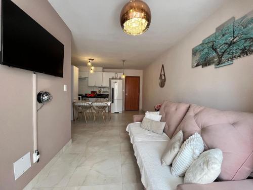 a living room with a couch and a flat screen tv at Bee Guest - Apartamentos de Temporada Luxxor Flat in Cuiabá