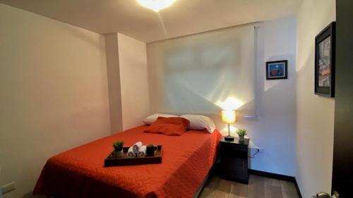 une chambre avec un lit avec un couvre-lit rouge dans l'établissement Petápolis 2 - Apartamento en el centro de la ciudad - Zona 12 de la Ciudad de Guatemala, à Guatemala