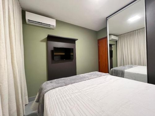 a bedroom with a bed and a mirror at Bee Guest - Apartamentos de Temporada Luxxor Flat in Cuiabá