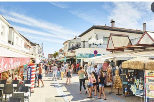Una multitud de personas caminando por una calle con tiendas. en Cozy 24 m studio near the sea, en La Tranche-sur-Mer