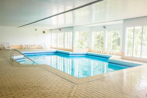 a large swimming pool with blue water in a building at Hotel Estancia Betania in Colombo