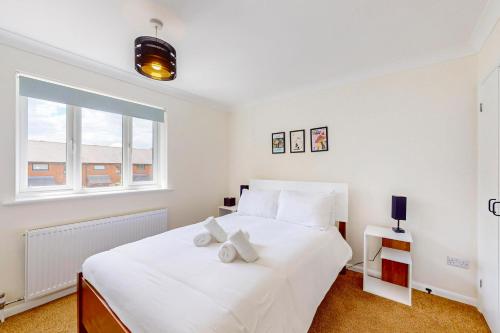 a bedroom with a large white bed and a window at 2 Bed with Garden & Free Parking near the Thames in London