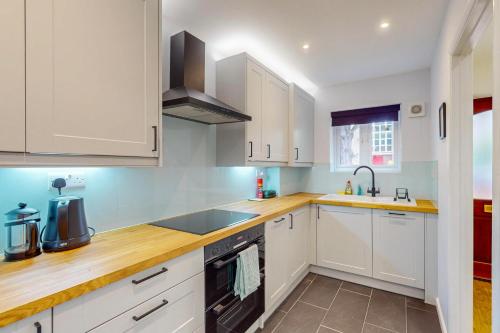 a kitchen with white cabinets and a sink at 2 Bed with Garden & Free Parking near the Thames in London