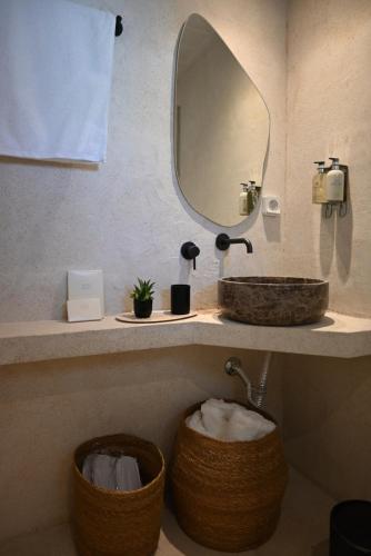 een badkamer met een wastafel, een spiegel en twee manden bij Kythnos Seaside House Flampouria in Kithnos