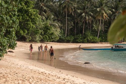 a group of people walking on a beach at Carve Bay Mentawai in Masokut