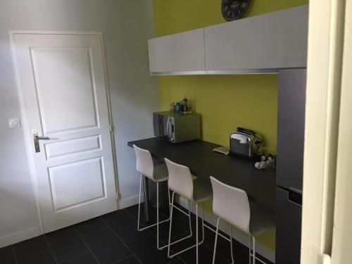 - une cuisine avec un comptoir avec des chaises et un four micro-ondes dans l'établissement Maison charmante près des plages de Capbreton avec jardin, à Capbreton