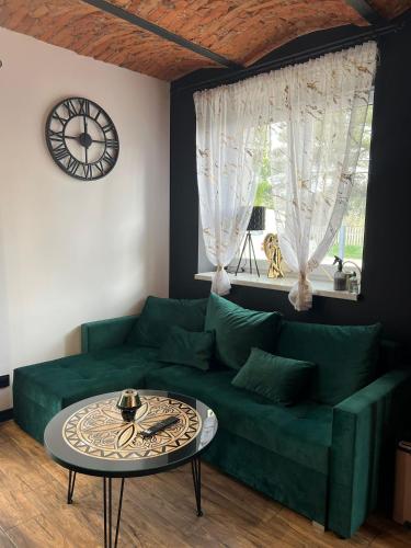 a living room with a green couch and a clock at Domek w górach in Załuczne