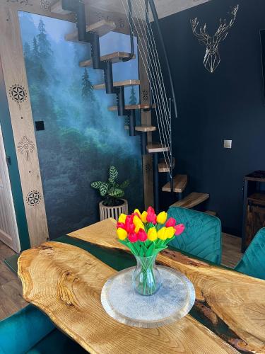 a vase of flowers on a table with a staircase at Domek w górach in Załuczne