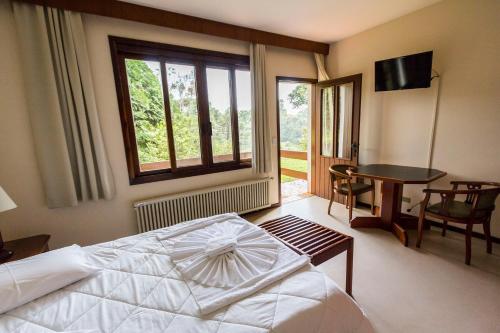 a bedroom with a bed and a table and a window at Hotel Estancia Betania in Colombo