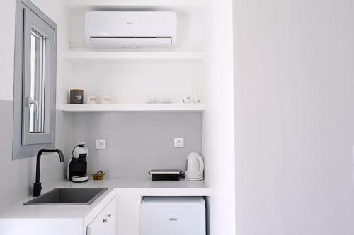 a white kitchen with a sink and a microwave at Cycladic Nest in Dryopida in Kithnos