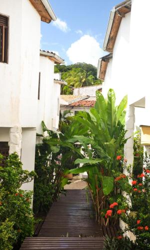 a wooden walkway between two buildings with plants at Pousada Prime Center in Pipa