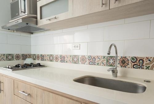 a white kitchen with a sink and a stove at Beautiful apt in Poblado-Tesoro Near Provenza! in Medellín