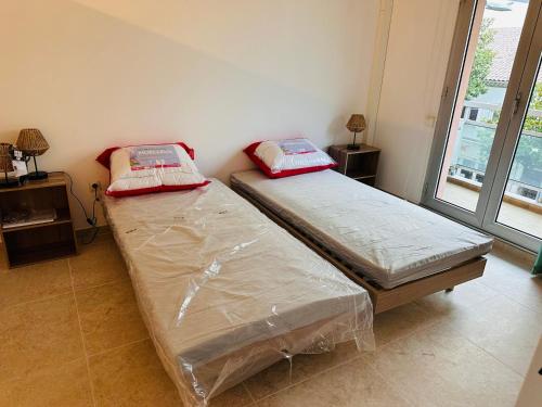 deux lits jumeaux dans une chambre avec fenêtre dans l'établissement Appartement Cavalaire proche de la mer , état neuf ,réservation 3 Jours minimum, à Cavalaire-sur-Mer