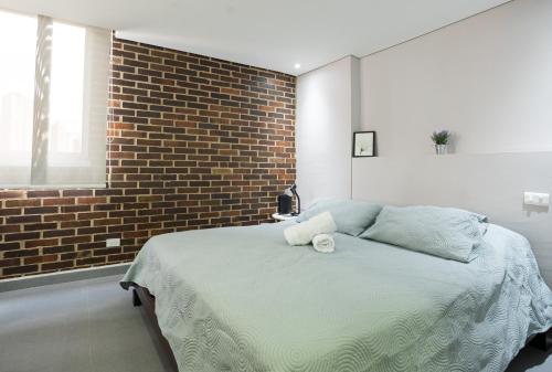 a bedroom with a large bed with a brick wall at Beautiful apt in Poblado-Tesoro Near Provenza! in Medellín