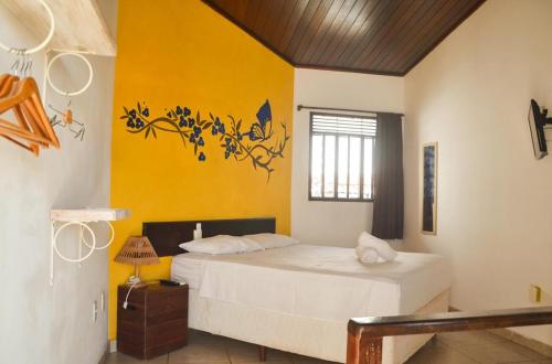 a bedroom with a bed and a yellow wall at Pousada Prime Center in Pipa