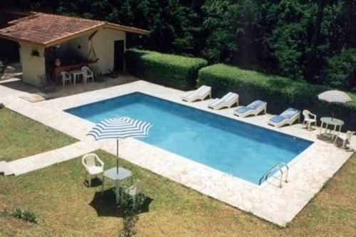 - une piscine avec des chaises et un parasol dans la cour dans l'établissement Pousada Passaredo, à Gonçalves