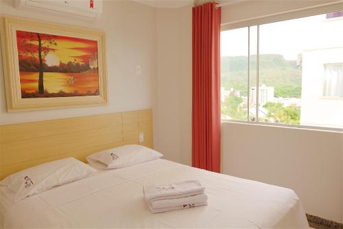 ein Schlafzimmer mit einem Bett mit weißen Laken und einem Fenster in der Unterkunft diRoma Rio Quente 1km do Hot Park in Rio Quente